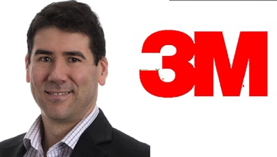 Smiling professional in business attire beside 3M corporate logo
