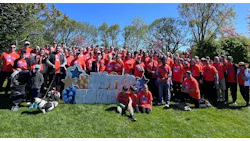 Community charity walk event with large group in orange shirts and '#STEP TO WIN' sign
