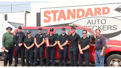 Firefighter team posing with red truck at Standard Auto Wreckers facility