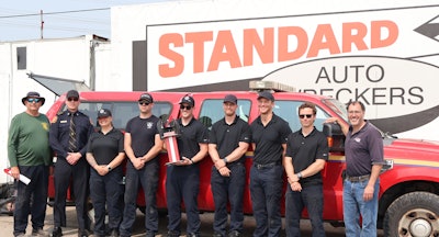 Firefighter team posing with red truck at Standard Auto Wreckers facility