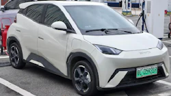 White electric BYD crossover SUV charging at a modern EV charging station