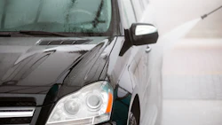 Black SUV with wet surface and illuminated headlight in rainy conditions
