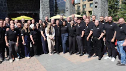 Corporate team gathering outdoors at mountain location, wearing matching black uniforms