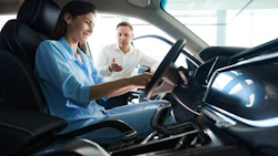 Car salesperson showing vehicle interior to potential customer