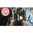 Skilled technician grinding metal with sparks, wearing safety gear in workshop