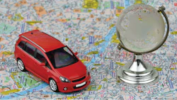 Red car on world map with glass globe, symbolizing travel and global mobility