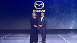 Two executives standing on stage at Mazda corporate event with starry blue background
