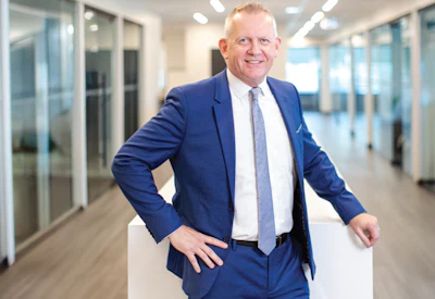 Smiling executive in blue suit standing in contemporary office space