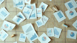 Business analytics documents with graphs and charts spread across a tiled floor