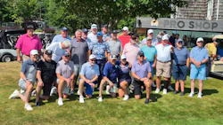 Large group of golfers posing together on a grassy lawn near a building