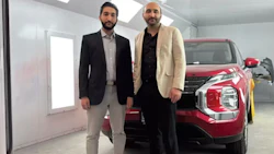 Two businessmen standing next to a red SUV in a bright automotive showroom