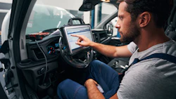 Auto technician using diagnostic tablet inside vehicle dashboard