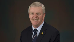 Smiling professional in navy suit with yellow awareness ribbon