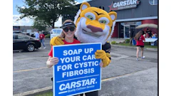 CARSTAR car wash fundraiser with mascot holding charity sign for cystic fibrosis