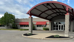 Modern building entrance with red-trimmed canopy and stone columns