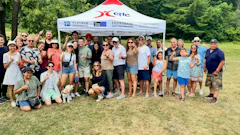 Large group of people gathered at outdoor event under corporate tent