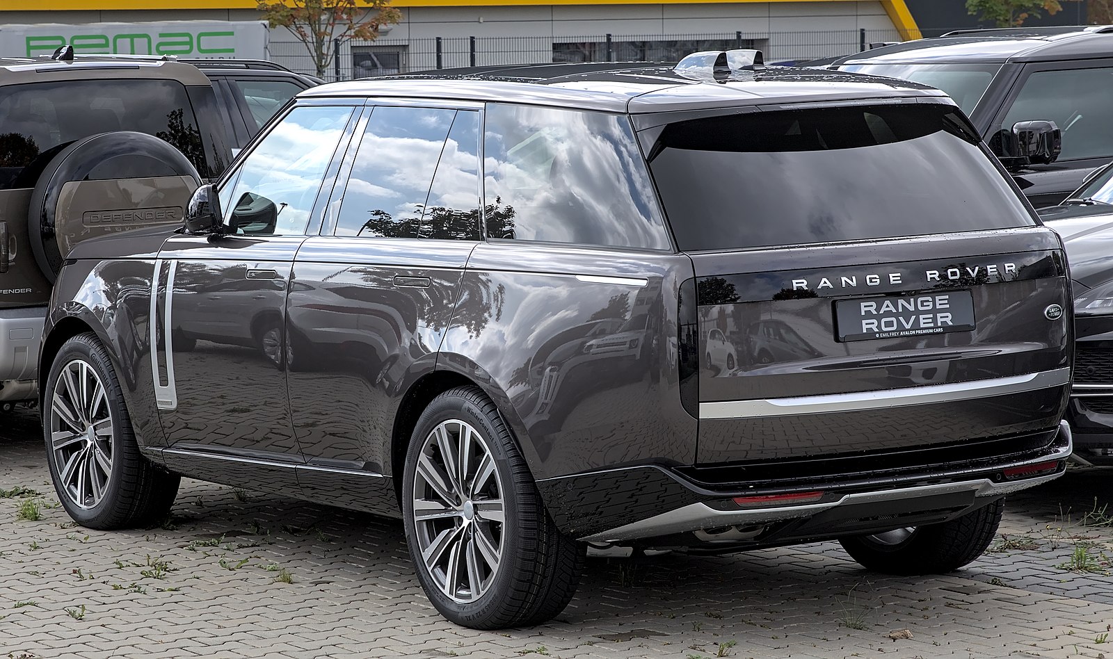 Gray Range Rover SUV parked on cobblestone surface with urban background