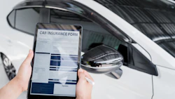 Tablet displaying car insurance form next to white vehicle side mirror