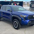 Blue Toyota pickup truck with black trim parked at racing facility