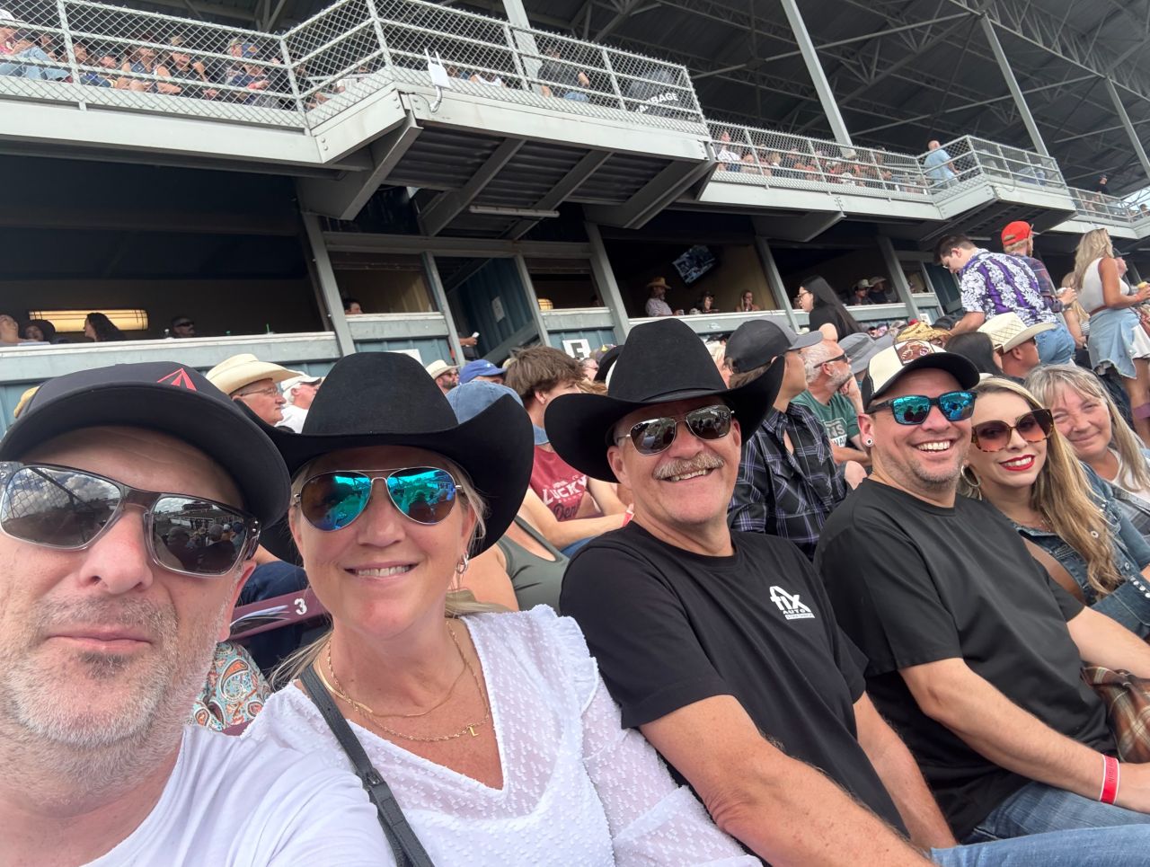 Group of friends wearing cowboy hats and sunglasses at outdoor stadium event