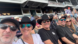 Group of friends wearing cowboy hats and sunglasses at outdoor stadium event