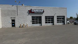 CARSTAR auto collision repair shop with white brick exterior and three garage doors