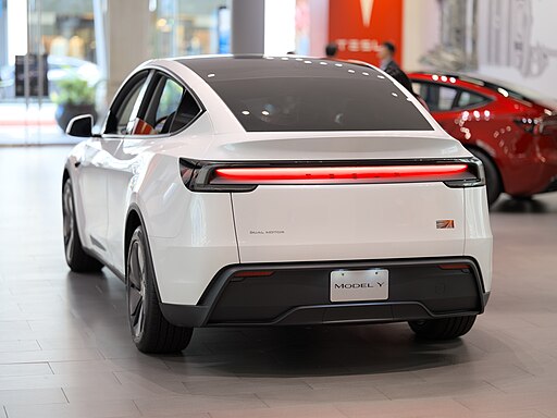 White Tesla Model Y electric SUV parked in modern automotive showroom