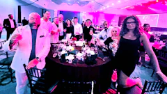 Festive event with guests gathered around a table under pink and blue lighting
