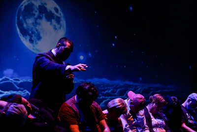 Presenter gesturing on stage with starry night and full moon backdrop