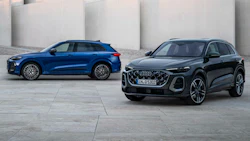 Two Audi SUVs - blue and black - parked on a concrete surface