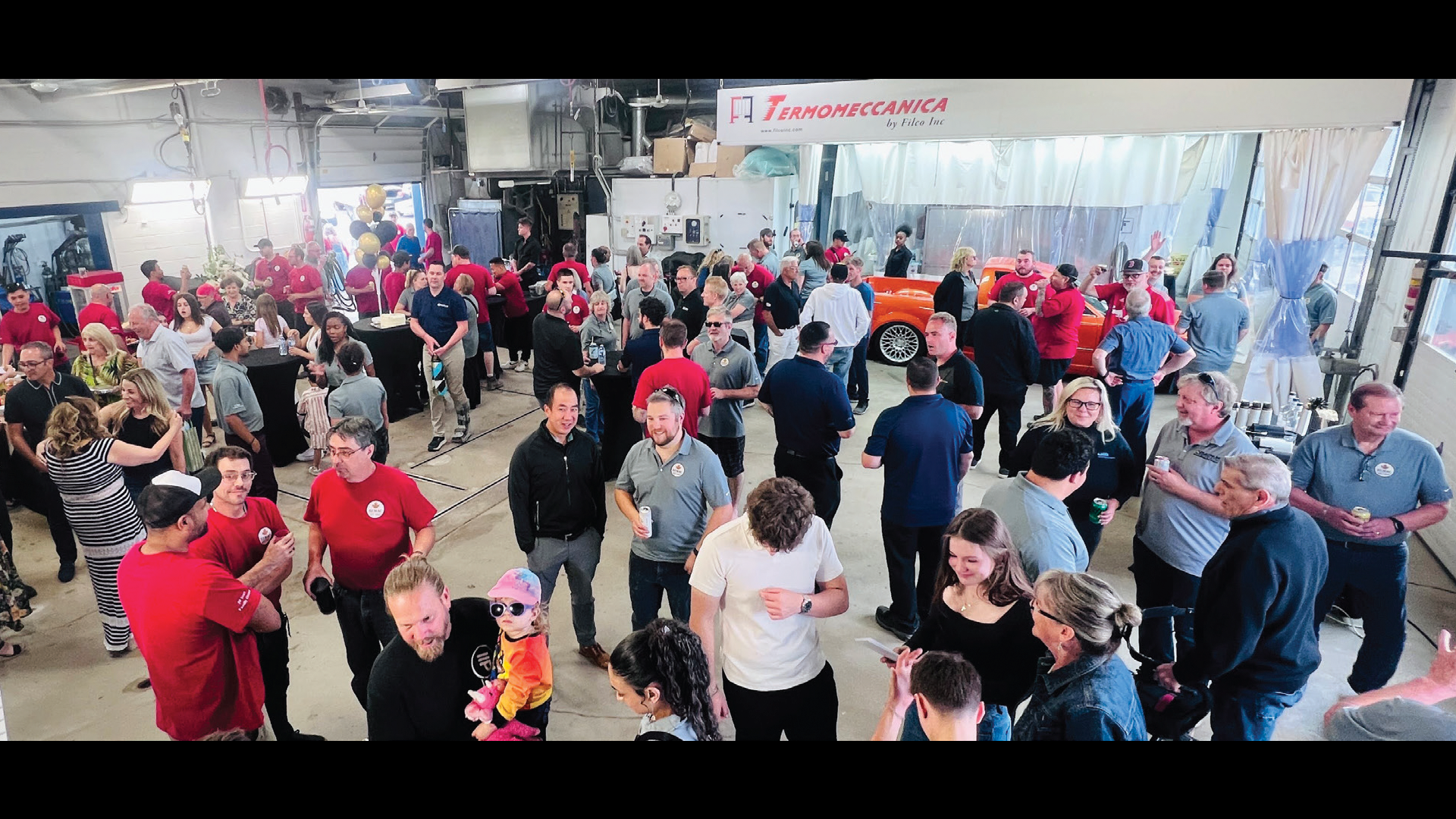 Large group event in industrial space with people mingling in red and blue clothing