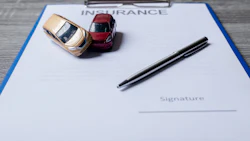 Insurance claim form with red and gold toy cars and a black pen