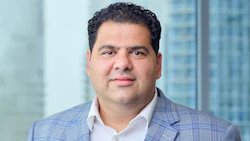 Professional man in blue plaid blazer standing in front of office windows