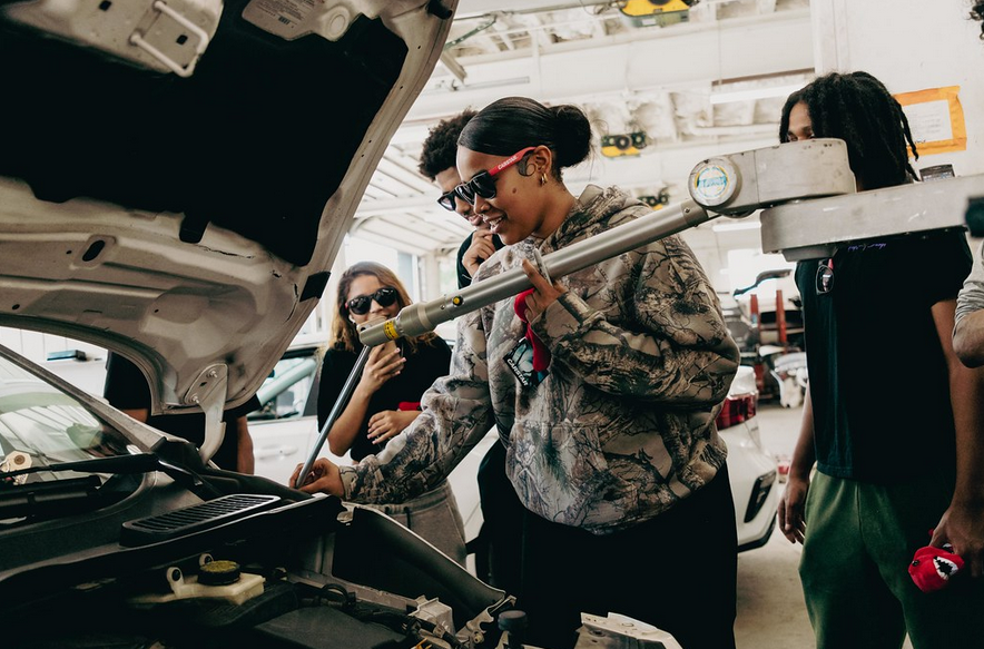 Automotive technicians in camouflage jacket examining car engine in repair shop