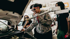 Automotive technicians in camouflage jacket examining car engine in repair shop
