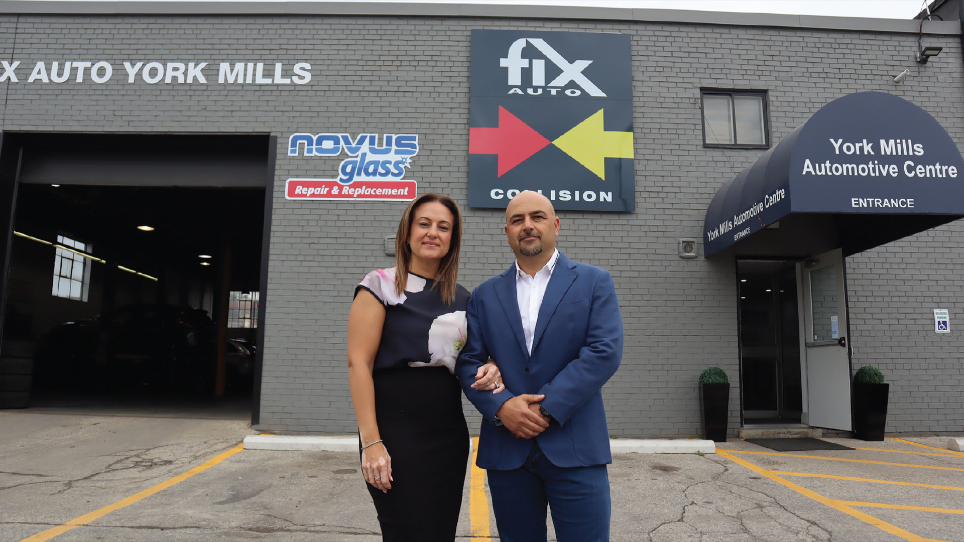 Two professionals standing outside York Mills Automotive Centre with Fix Auto and Novus Glass signs