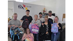Fix Auto Team group photo with employees holding colorful backpacks