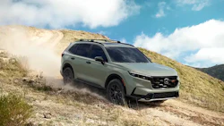 Green Honda SUV driving on dusty mountain terrain with cloudy sky