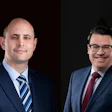Two businessmen in navy suits, one bald and one wearing glasses, against dark backgrounds