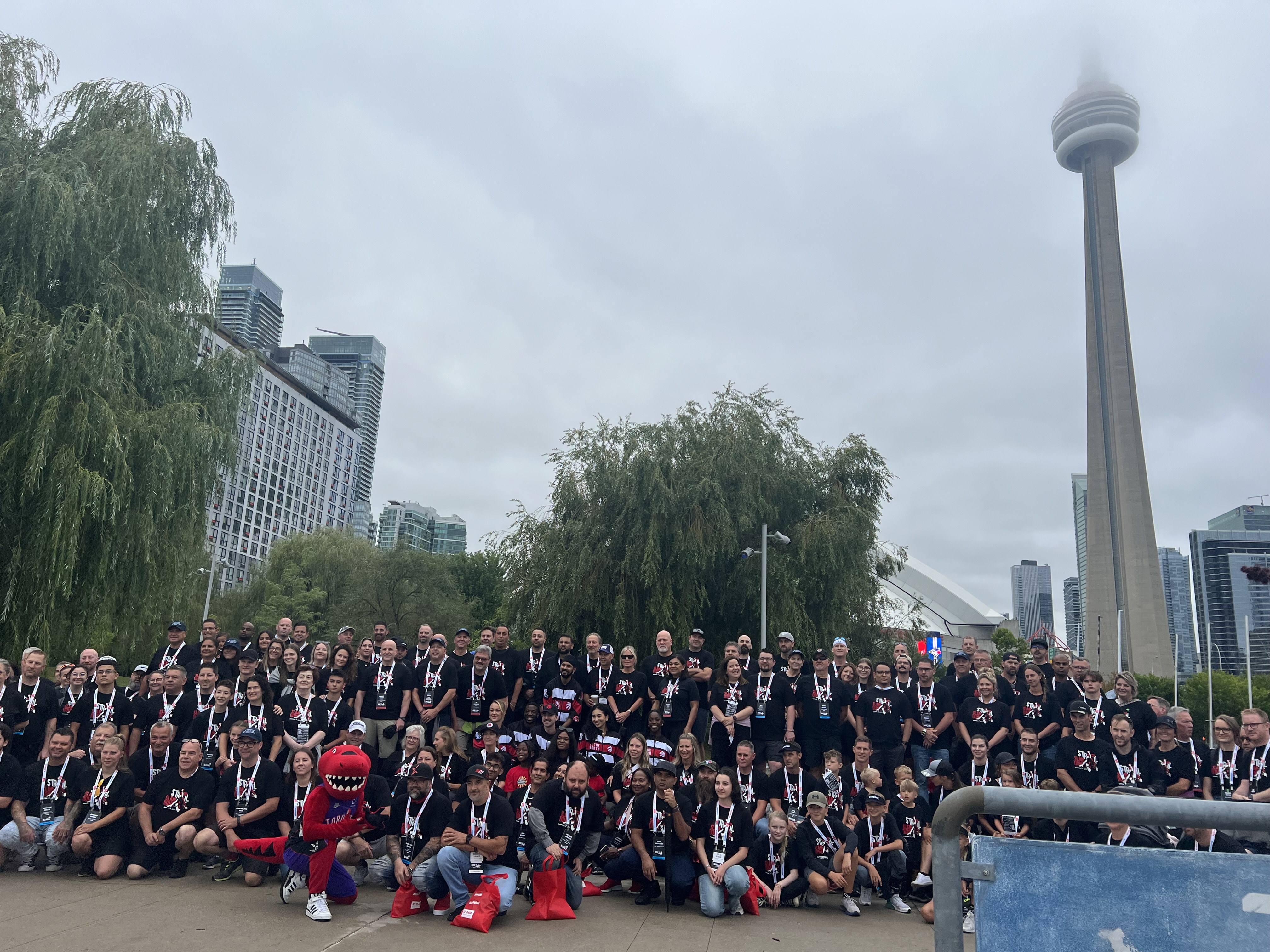 Large group of people in black shirts gathered outdoors near CN Tower in Toronto