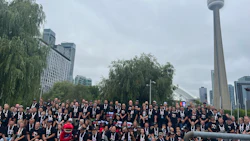 Large group of people in black shirts gathered outdoors near CN Tower in Toronto