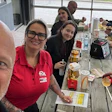 Group of colleagues enjoying lunch at a wooden table with food and drinks