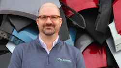 Professional wearing glasses in gray zip-up shirt standing near industrial machinery