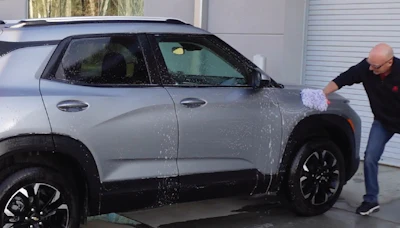 Silver SUV being hand-washed with a white cleaning mitt in a garage