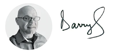 Bald man with glasses in collared shirt, next to handwritten signature