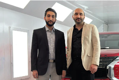 Two men in business attire standing in a modern automotive showroom with natural lighting