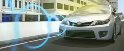 White Toyota sedan demonstrating advanced driver assistance technology on urban street