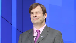 Professional man in gray suit and pink tie smiling at corporate event