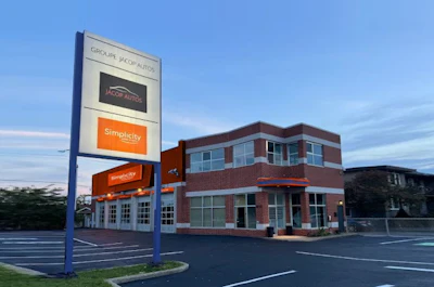 Brick office building with Groupe Jacob Autos signage in parking lot at dusk
