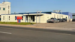 Simplicity business building with red logo sign, parked trucks, and clear blue sky